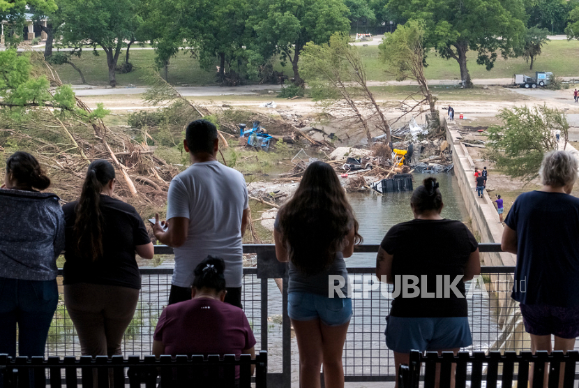 Para penonton melihat ke bawah ke kerusakan di sepanjang Sungai Guadalupe yang disebabkan oleh banjir baru-baru ini, Minggu, 6 Juli 2025, di Kerrville, Texas.