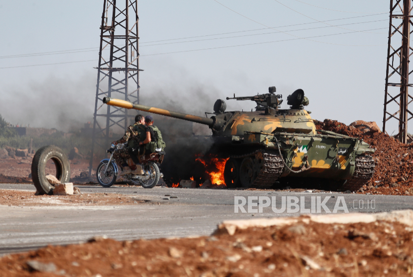 Tentara pemerintah Suriah melewati tank yang terbakar di pinggiran kota Sweida, di Suriah selatan, Senin, 14 Juli 2025.