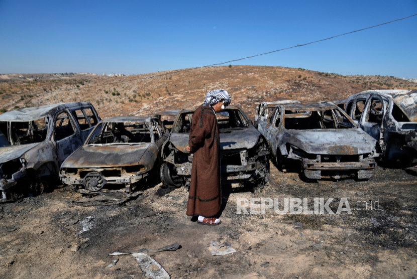 Pemilik tanah Palestina, Saber Asaleyeh, 74 tahun, memeriksa rongsokan mobilnya yang hangus akibat serangan pemukim Israel di desa Tepi Barat Burqa, Selasa, 15 Juli 2025.
