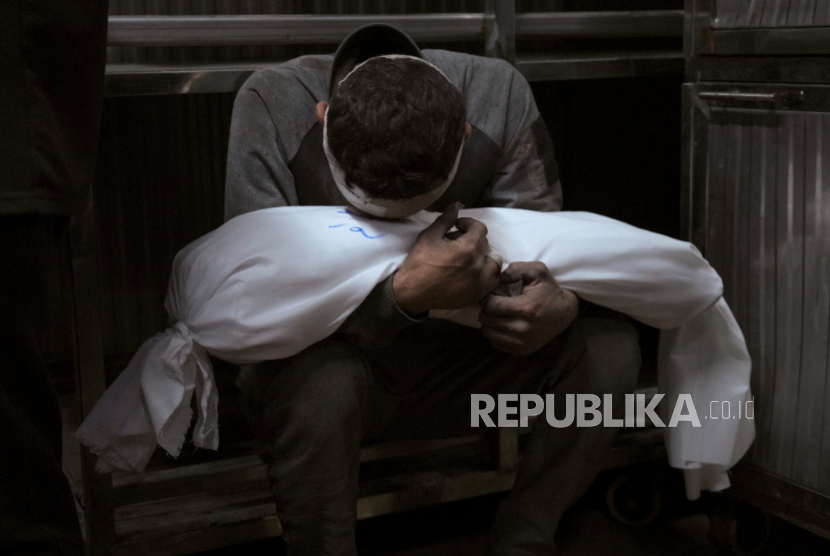 Hossam Azzam memegang jasad anaknya, Amir, yang terbunuh dalam serangan udara militer Israel di Gaza, di Rumah Sakit Shifa di Kota Gaza, Selasa, 15 Juli 2025.