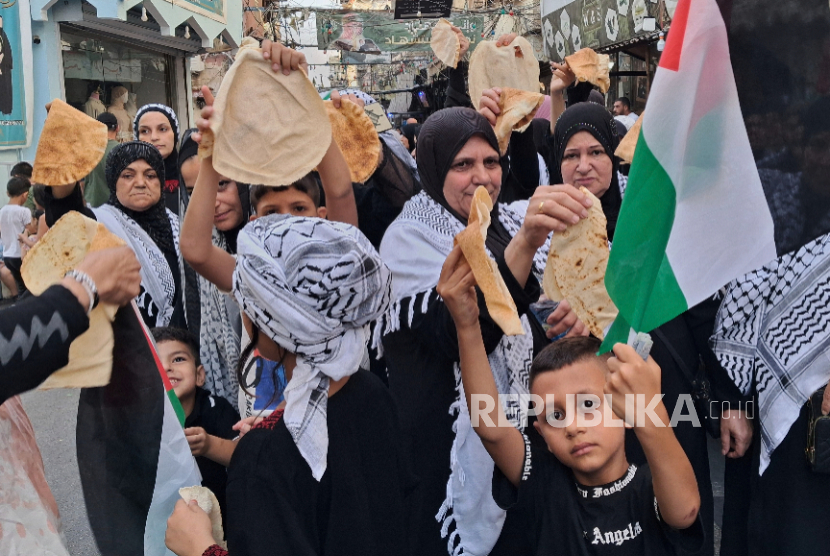 Warga Palestina memegang potongan roti selama protes terhadap kondisi kelaparan buatan Israel di Gaza di Sidon, Lebanon, Ahad, 20 Juli 2025. 