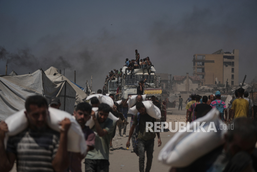 Warga Palestina membawa karung tepung yang diturunkan dari konvoi bantuan kemanusiaan yang mencapai Kota Gaza dari Jalur Gaza utara, Ahad, 27 Juli 2025.