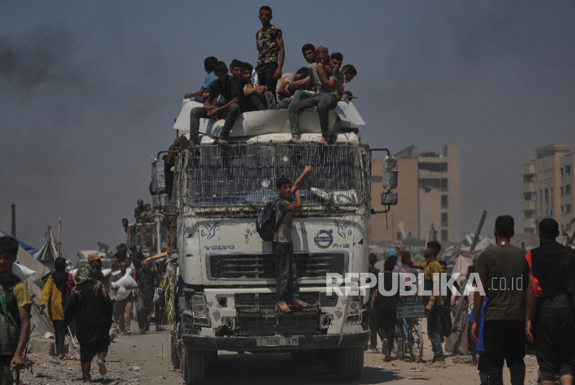 Warga Palestina membawa karung tepung yang diturunkan dari konvoi bantuan kemanusiaan yang mencapai Kota Gaza dari Jalur Gaza utara, Minggu, 27 Juli 2025.