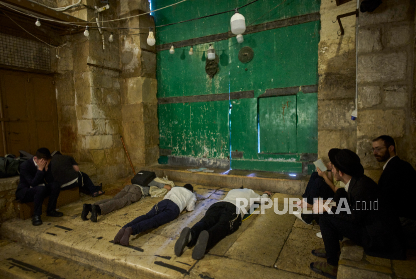 Pria Yahudi ultra-Ortodoks berdoa selama ritual berkabung puasa Tisha BAv di samping salah satu gerbang menuju Masjid Al-Aqsa di Kota Tua Yerusalem, Ahad, 3 Agustus 2025 .