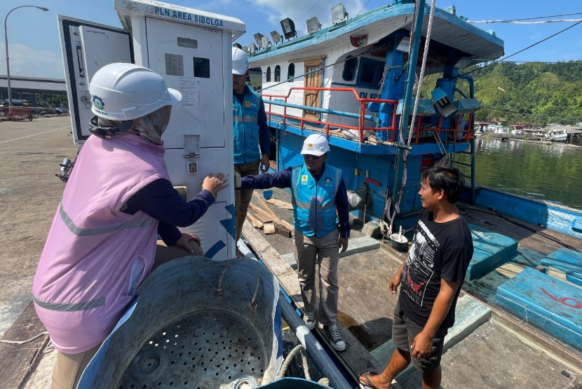 Petugas PLN (kiri) ketika sedang berbincang dengan salah seorang pemilik kapal ikan, Hutagalung (kanan) yang sedang menggunakan ALMA sebagai bagian dari program Electrifying Marine saat kapalnya bersandar di Tempat Pelelangan Ikan (TPI) Kecamatan Sarudik, Kabupaten Tapanuli Tengah, Sumatera Utara.