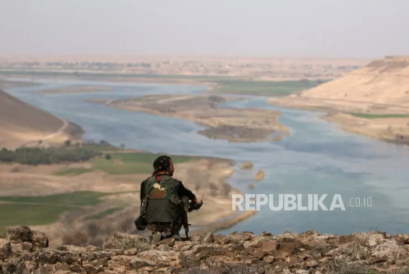 Pejuang Suriah duduk memandangi Sungai Eufrat yang mengering di Raqqa.