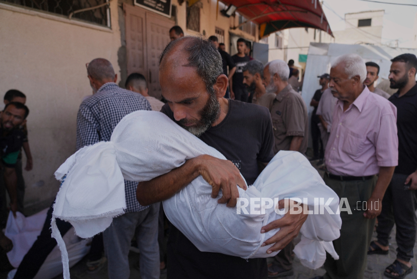 Ahmed Al-Hajj membawa jenazah putrinya, Dana Al-Hajj (13 tahun), yang syahid dalam serangan udara Israel di Jalur Gaza, di Rumah Sakit Al-Aqsa di Deir al-Balah, Selasa, 19 Agustus 2025.