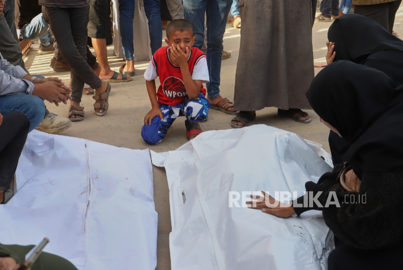 Seorang anak laki-laki Palestina berduka atas jenazah paman dan sepupunya yang akibat serangan udara Israel, saat pemakaman di Khan Younis, di selatan Jalur Gaza, Selasa, 19 Agustus 2025.