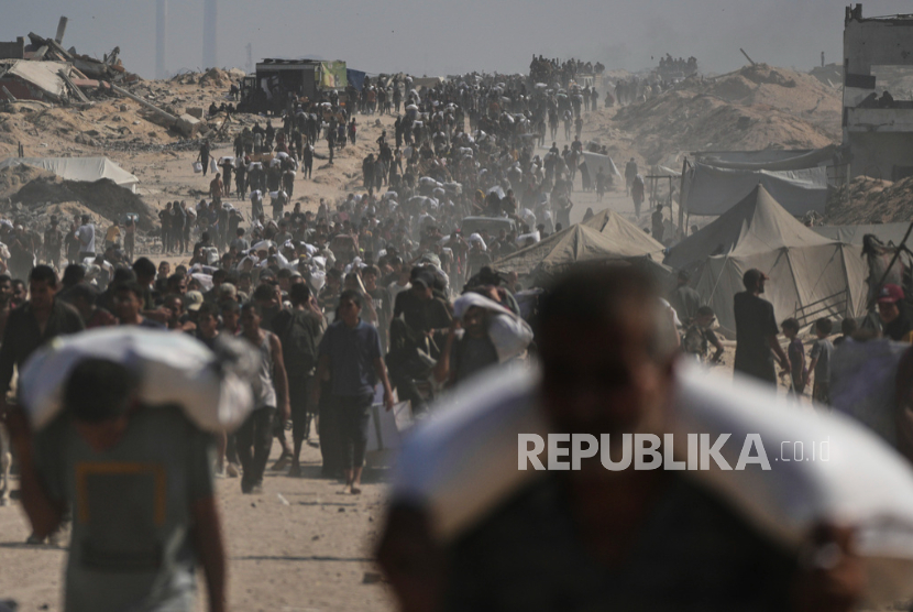 Warga Palestina membawa karung tepung yang diturunkan dari konvoi bantuan kemanusiaan di pinggiran Beit Lahiya, Jalur Gaza utara, Sabtu, 23 Agustus 2025.
