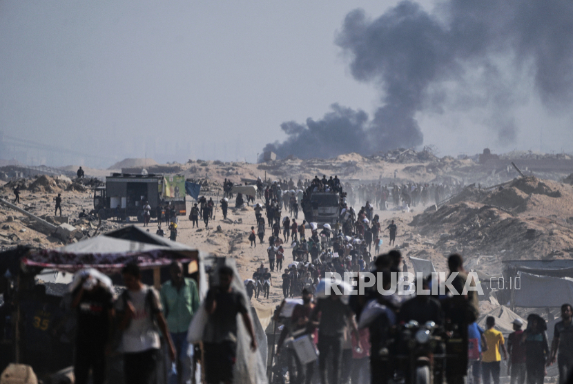 Warga Palestina membawa karung tepung yang diturunkan dari konvoi bantuan kemanusiaan di pinggiran Beit Lahiya, Jalur Gaza utara, Sabtu, 23 Agustus 2025. 