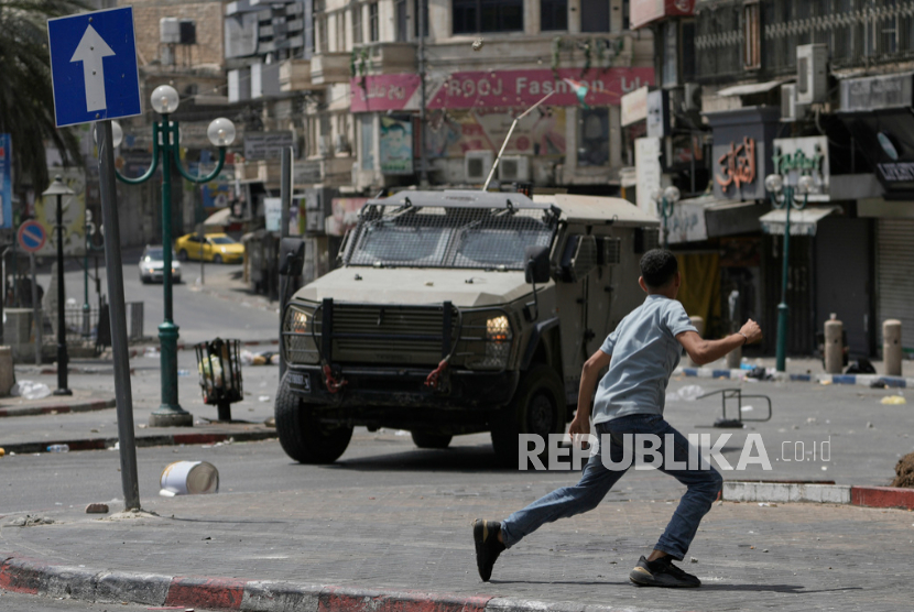 Anak Palestina menghalau kendaraan Israel selama bentrokan dengan pasukan Israel menyusul serangan militer di kota Nablus, Tepi Barat, Rabu, 27 Agustus 2025. 