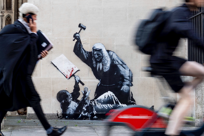 Karya mural baru Banksy yang menggambarkan seorang hakim memukul seorang pengunjuk rasa dengan palu di Pengadilan Kerajaan di London. 