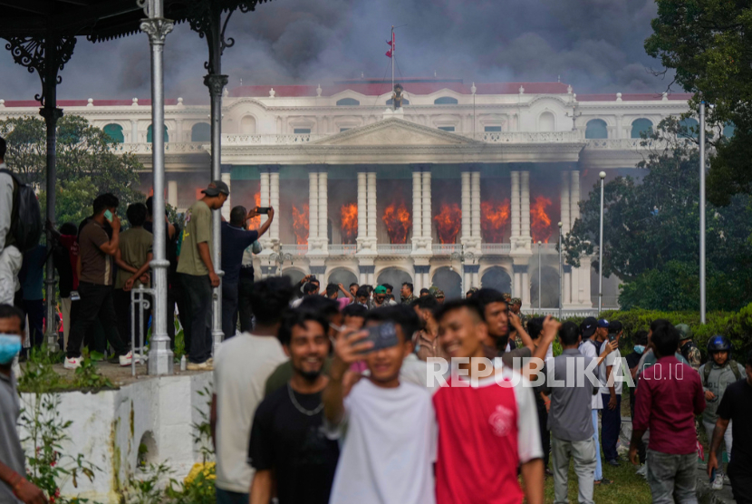 Pengunjuk rasa berswafoto di depan Singha Durbar, pusat berbagai kementerian dan kantor pemerintah Nepal, setelah tempat itu dibakar di Kathmandu, Nepal, Selasa, 9 September 2025.