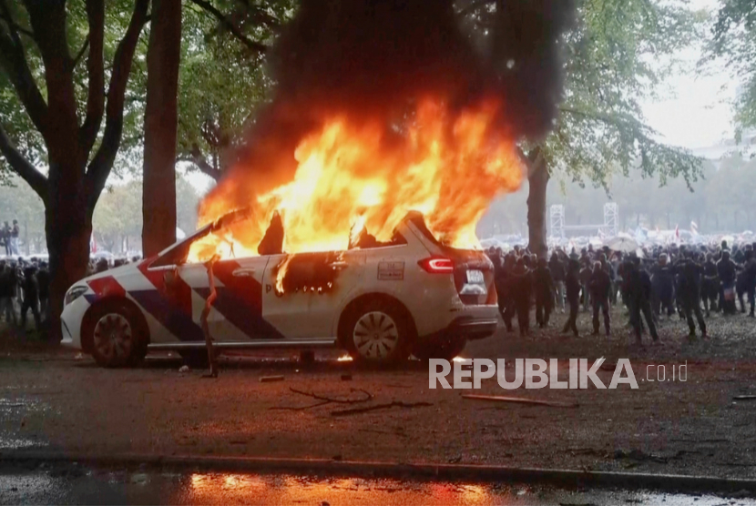Sebuah kendaraan polisi terbakar saat demonstrasi sayap kanan meletus menjadi kekerasan dan kekacauan saat perusuh bentrok dengan polisi pada Sabtu, 20 September 2025 di Den Haag, Belanda.