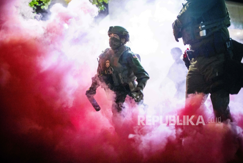 Polisi dan petugas federal melemparkan tabung gas untuk membubarkan pengunjuk rasa di dekat fasilitas Imigrasi dan Bea Cukai AS di Portland, Oregon pada Ahad, 5 Oktober 2025. 