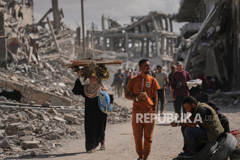 Pengungsi Palestina berjalan melewati bangunan yang hancur saat mereka kembali ke rumah mereka di Khan Younis, Jalur Gaza selatan, Jumat, 10 Oktober 2025.