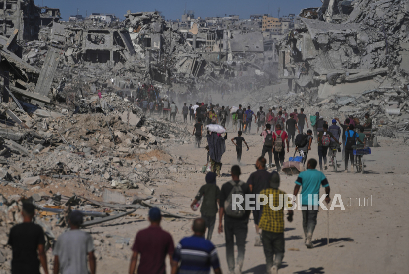 Pengungsi Palestina berjalan melewati bangunan yang hancur saat mereka kembali ke rumah mereka di Khan Younis, Jalur Gaza selatan, Jumat, 10 Oktober 2025.