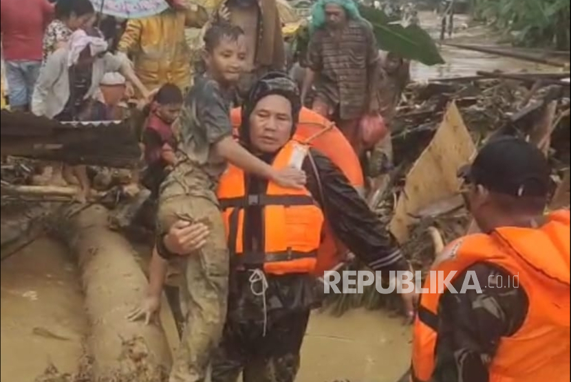 Personel Koramil 01/Batangtoru di bawah Kodim 0212/Tapanuli Selatan (Tapsel), Kodam Bukit Barisan membantu evakuasi warga korban banjir.