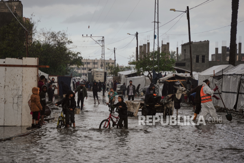 Pengungsi Palestina membersihkan air dari tenda mereka yang kebanjiran di kamp sementara setelah hujan lebat di Kota Gaza Selasa, 25 November 2025.