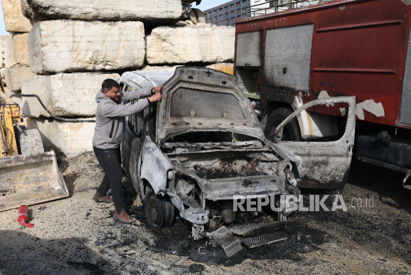 Seorang warga Palestina memeriksa dampak kebakaran yang dilakukan oleh pemukim Israel yang merusak mobil, di desa Awarta, selatan Nablus di Tepi Barat, 21 Januari 2026. 