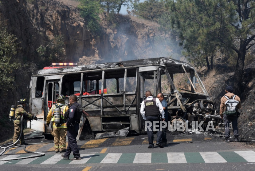 Aparat di dekat sebuah kendaraan yang dibakar gangster setelah pembunuhan Nemesio Oseguera Cervantes, yang dikenal sebagai El Mencho, pemimpin Kartel Generasi Baru Jalisco, di Morelia, Meksiko, 22 Februari 2026. 