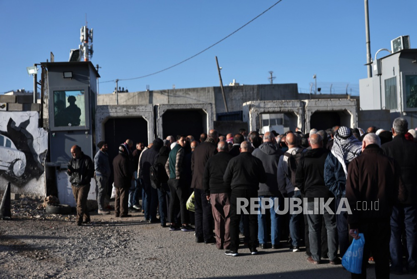 Tentara Israel berjaga ketika warga Palestina mengantri untuk menyeberang di pos pemeriksaan Israel di Qalandia antara Tepi Barat dan Yerusalem, 20 Februari 2026