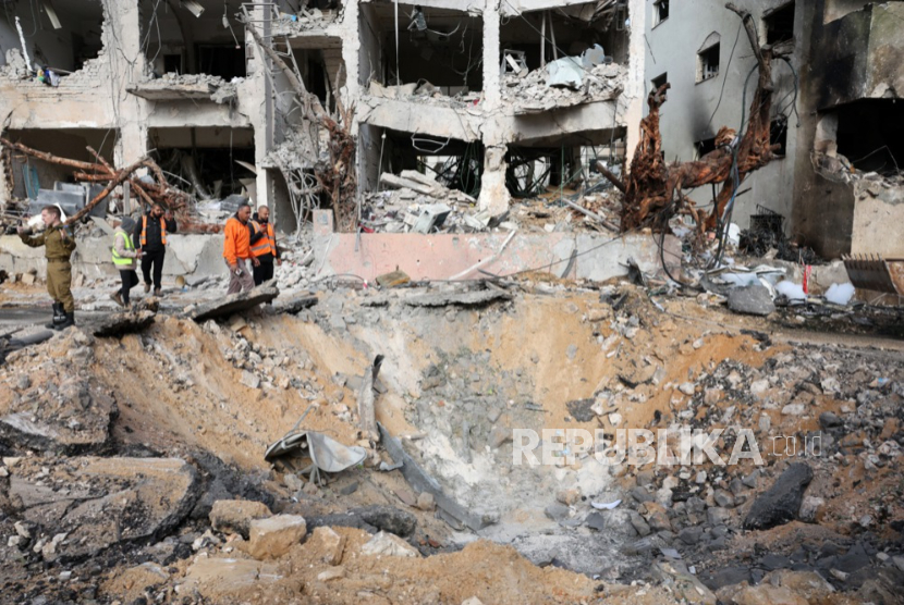 Personel layanan darurat memeriksa kerusakan di lokasi sebuah bangunan yang terkena rudal Iran di Tel Aviv, Israel, 1 Maret 2026.