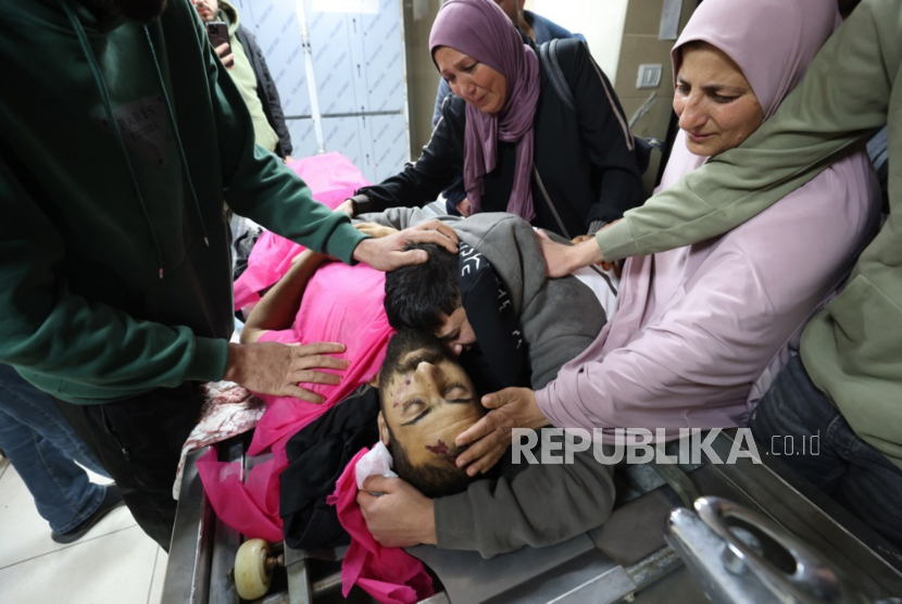 Jenazah Amir Moatasem Mahmoud Odeh (25 tahun) yang yang syahid dibunuh pemukim Israel dipeluk keluarganya di RS Rafedya di kota Nablus, Tepi Barat, 14 Maret 2026. 