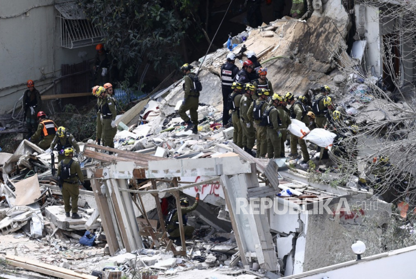 Tim penyelamat Israel membawa jenazah di lokasi bangunan tempat tinggal yang terkena serangan rudal Iran di Haifa, Israel, 06 April 2026. 