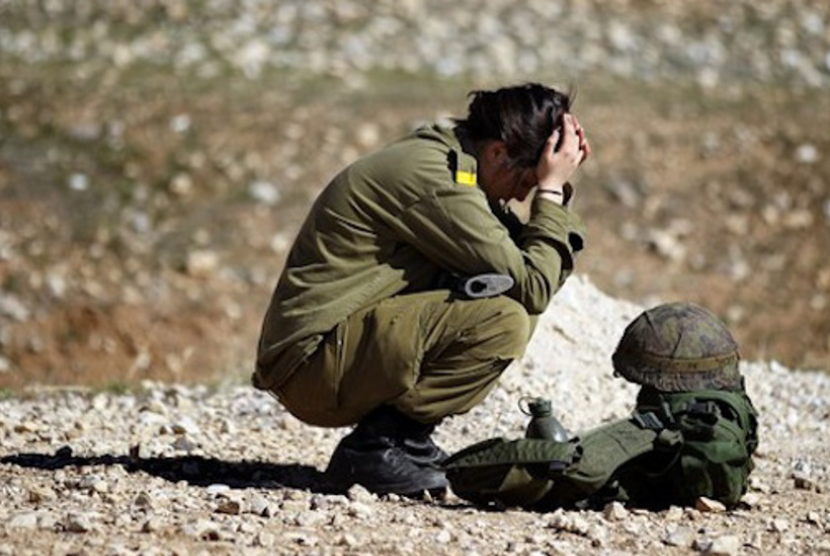Seorang tentara tempur wanita muda Israel beristirahat setelah mengikuti latihan rintangan.