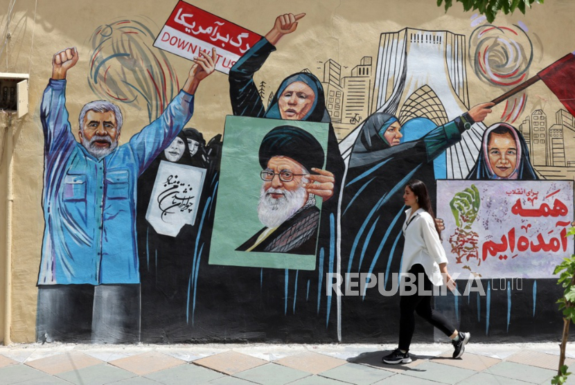 Seorang warga Iran berjalan di samping mural anti-AS dan Israel di sebuah jalan di Teheran, Iran, 8 Mei 2026. 