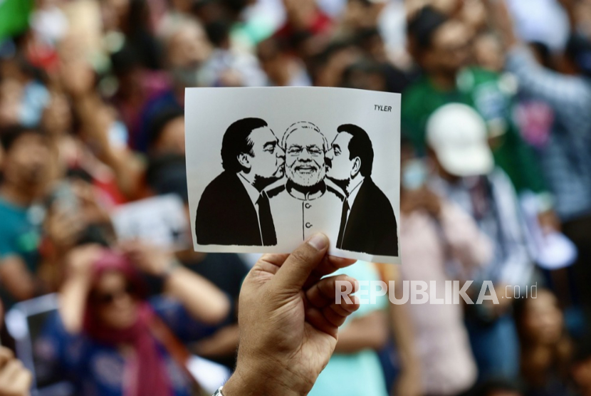 Seorang pengunjuk rasa memegang poster yang menampilkan Perdana Menteri India Narendra Modi (tengah) saat ia dicium oleh pengusaha India Mukesh Dhirubhai Ambani (kiri) dan miliarder India sekaligus Chairman Adani Group, Gautam Adani (kanan), dalam sebuah aksi unjuk rasa di Bangalore, India, pada 25 Juli 2026.