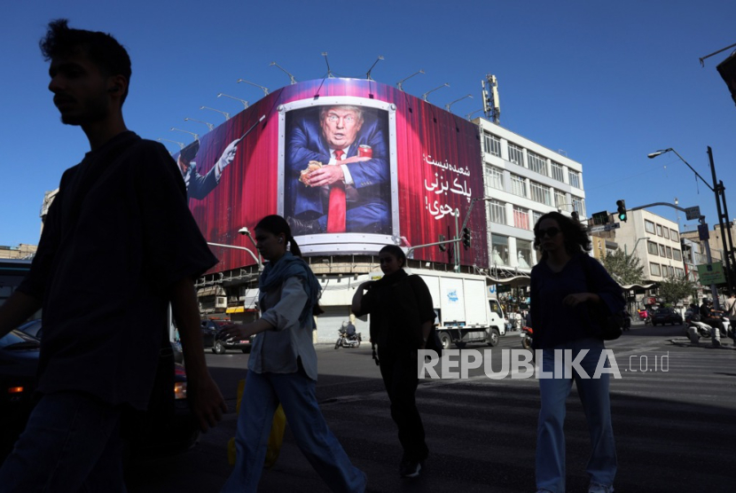 Warga Iran berjalan melewati papan reklame anti-Trump di sebuah jalan di Teheran, Iran, pada 23 September 2026.