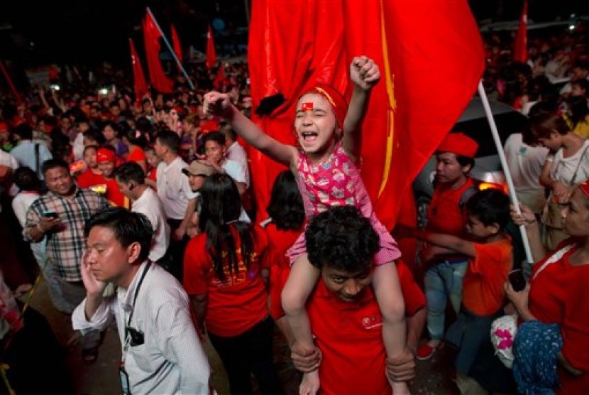A child joins adult supporters of Myanmar's National League for Democracy party to celebrate as unofficial election results are posted outside the NLD headquarters in Yangon, Myanmar, Monday, Nov. 9, 2015. 