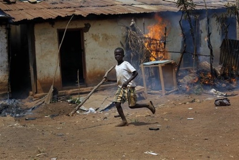 A child runs by a burning house as Anti-Balaka Christan youth loot the Muslim market in the PK13 district of Bangui, Central African Republic, Wednesday, Jan. 22, 2014.