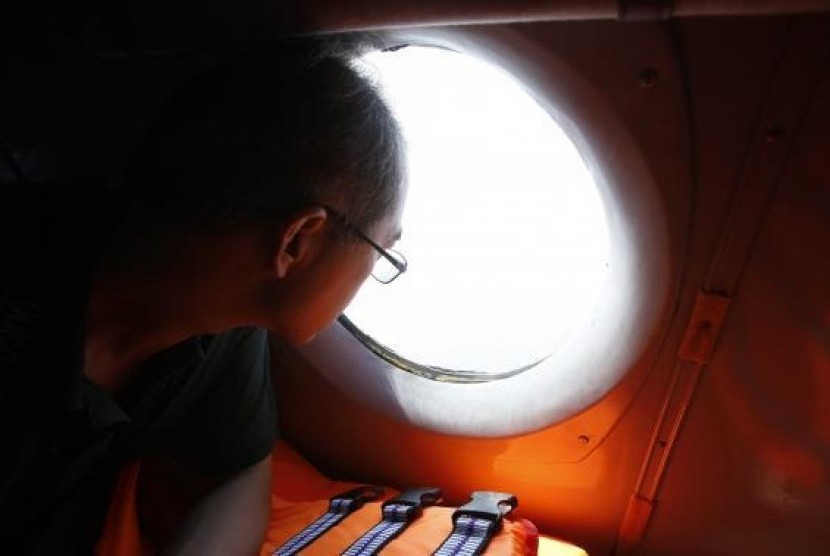 A Chinese journalist looks out from the window of a Vietnamese airforce AN-26 during a mission to find the missing Malaysia Airlines flight MH370 off Tho Chu islands March 11, 2014.