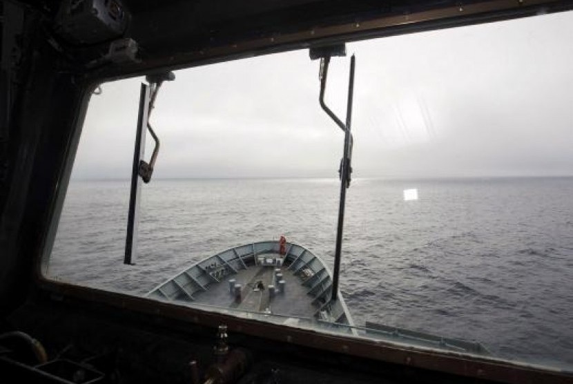 A crew member aboard the Australian Navy ship, HMAS Success, can be seen through a window looking for debris in the southern Indian Ocean during the search for missing Malaysia Airlines Flight MH370.