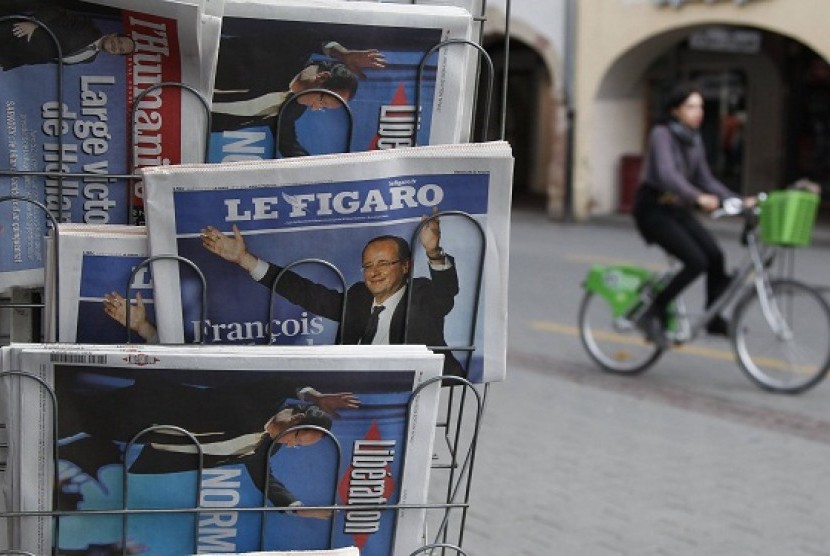 A cyclist rides past a news rack displying copies of French daily newspapers with front pages featuring France's newly-elected President in Strasbourg May 7, 2012, the day after Socialist party Francois Hollande won French presidency.   