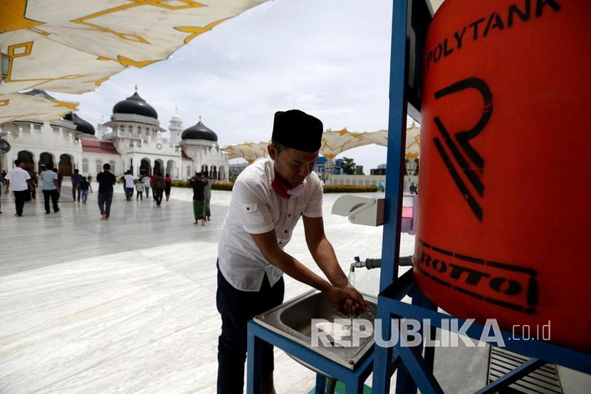  Seorang jamaah mencuci tangan sebelum memasuki area Masjid Raya Baiturrahman untuk melaksanakan ibadah shalat Jumat di Masjid Raya Baiturrahman, Banda Aceh, Aceh, Jumat (29/5/2020). 
