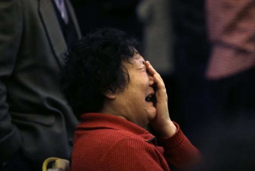 A family member of a passenger onboard Malaysia Airlines Flight MH370 covers her face as she cries after a routine briefing given by Malaysia Airlines in Beijing, March 22, 2014. 