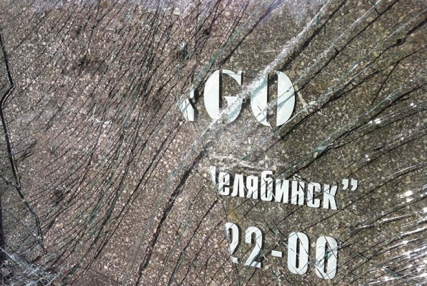 A fragment of a broken door glass, currently placed near an entrance to a fashion and clothes store, which was damaged by a shockwave from a meteorite, is seen in the centre of the Urals city of Chelyabinsk on Sunday.