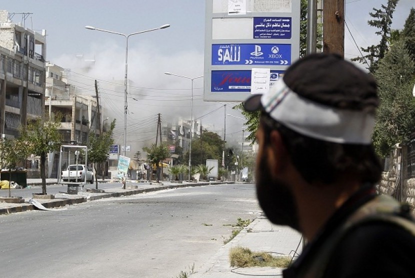 A Free Syrian Army fighter looks at a building shelled by Syrian Army mortar in Aleppo August 15, 2012.   