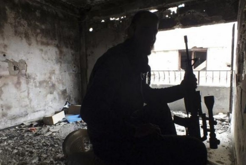 A Free Syrian Fighter holds his weapon inside a damaged building in the besieged area of Homs, January 4, 2014.