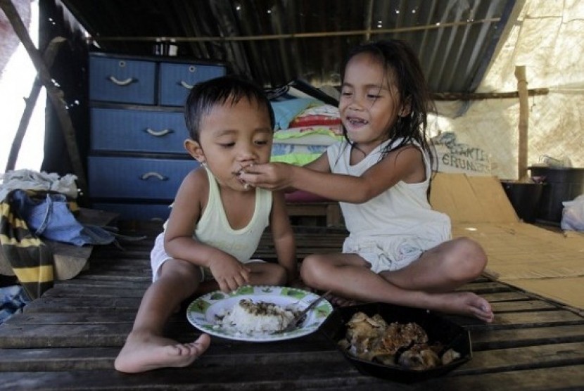 A girl feeds her brother inside a makeshift shelter for Typhoon Bopha victims in New Bataan, southern Philippines December 12, 2012. 