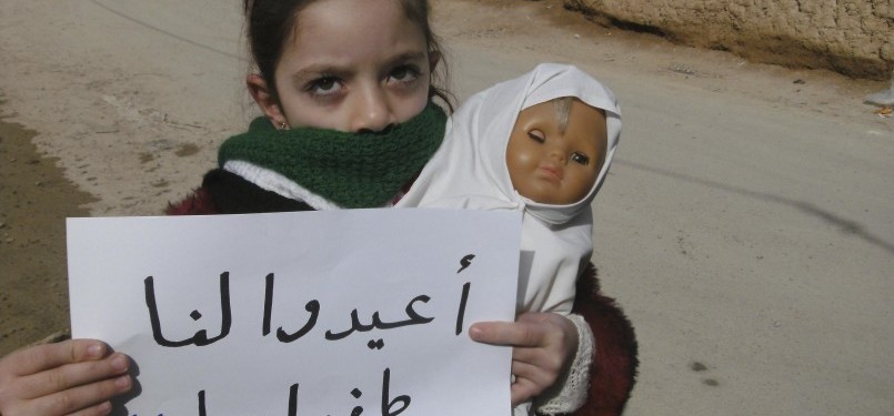 A girl holds a doll and a banner during a protest against Syria's President Bashar al-Assad in Daria, near Damascus, February 12, 2012. The banner reads: 