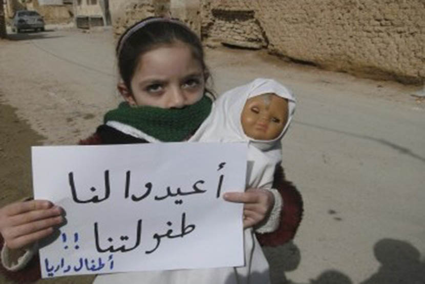 A girl holds a doll and a banner during a protest against Syria's President Bashar al-Assad in Daria, near Damascus, February 12, 2012. The banner reads: Bring back our childhood.