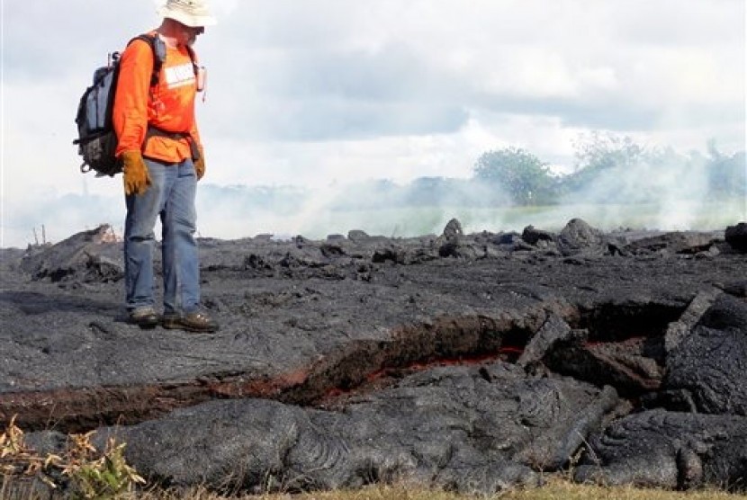 A Hawaii Volcano Observatory geologist standing on a partly cooled section of lava flow near the town of Pahoa on the Big Island of Hawaii on Oct 25, 2014.