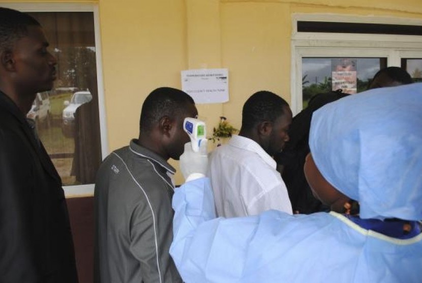 A health worker takes the temperature of people at a news conference on the opening of a new Ebola clinic, outside Monrovia October 3, 2014.