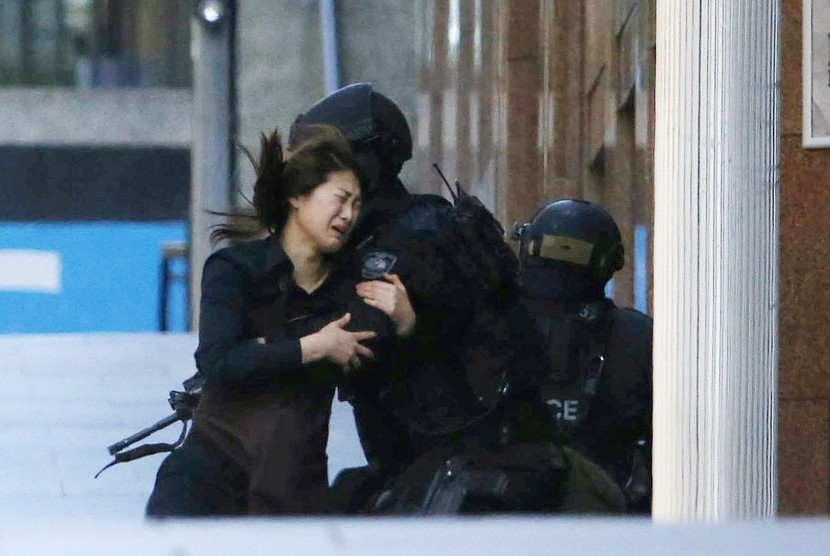 A hostage runs towards a police officer outside Lindt cafe, where other hostages are being held, in Martin Place in central Sydney December 15, 2014. 