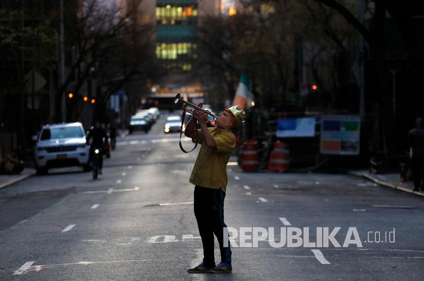 A man blows a trumpet in the street during a citywide show of support, taking place each night at 7pm for essential workers on the frontlines of the current health crisis, in New York, New York, USA, 09 April 2020. New York City is still the epicenter of the coronavirus outbreak in the United States and the city is still trying to get people to either stay at home or maintain a safe distance from each other.  